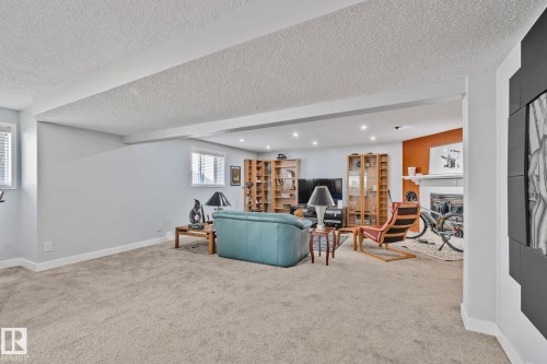 Carpeted living area with recessed lighting, built-in shelving, a fireplace, and multiple windows - 18812 89 Avenue Nw, Edmonton, AB 