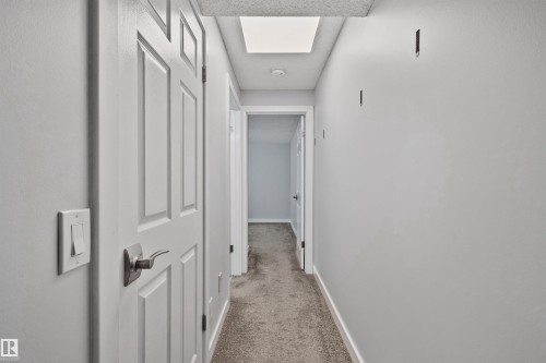 Hallway featuring light gray wall paint, white trim, and carpet flooring - 18812 89 Avenue Nw, Edmonton, AB 