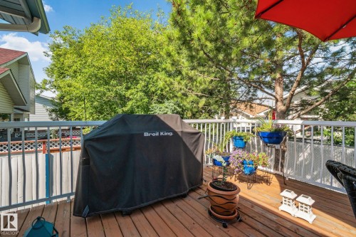 Rear Deck located off of the kitchen. Wood-finish deck with white railings and mature trees - 18812 89 Avenue Nw, Edmonton, AB 