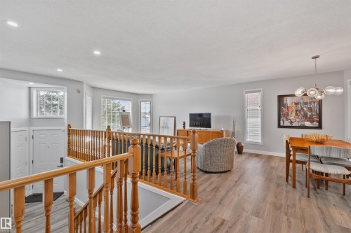 Wood-finish flooring throughout, light gray wall tones, recessed ceiling lighting, and a contemporary dining chandelier - 18812 89 Avenue Nw, Edmonton, AB 