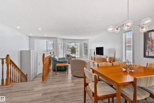 Open-concept living area with wood-finish flooring, a contemporary chandelier, and a bay window - 18812 89 Avenue Nw, Edmonton, AB 