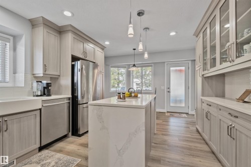 Kitchen featuring a central island with a solid surface countertop, wood-finish flooring, recessed lighting, and pendant light fixtures - 18812 89 Avenue Nw, Edmonton, AB 