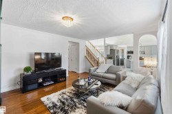Hardwood flooring, crystal flush mount lighting, painted wood staircase with wood handrail, arched doorway, and crown molding - 