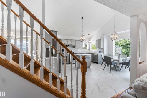 Wood-finish staircase with white balusters, vaulted ceilings, and large windows - 522 Klarvatten Lake Wynd Nw, Edmonton, AB 