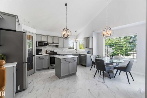 Vaulted ceilings complement the kitchen's light gray cabinetry, stainless steel appliances, and white stone-finish countertops - 522 Klarvatten Lake Wynd Nw, Edmonton, AB 