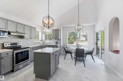 Kitchen featuring gray cabinetry, stainless steel appliances, a chevron-patterned backsplash, and light-toned stone countertops - 
