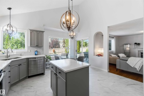 Kitchen featuring vaulted ceilings, pendant light fixtures, stainless steel appliances, and a central island with countertop space - 522 Klarvatten Lake Wynd Nw, Edmonton, AB 