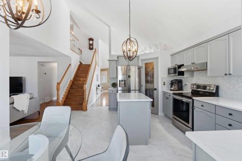 Open-concept kitchen with light gray cabinetry, stainless steel appliances, white countertops, and a herringbone tile backsplash - 522 Klarvatten Lake Wynd Nw, Edmonton, AB 