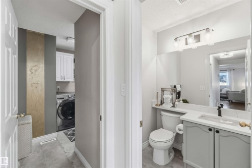 Bathroom featuring a vanity with a white countertop and a dark-finished faucet, a wall-mounted light fixture, and a toilet - 522 Klarvatten Lake Wynd Nw, Edmonton, AB 