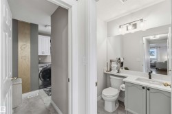 Bathroom featuring a vanity with a white countertop and a dark-finished faucet, a wall-mounted light fixture, and a toilet - 
