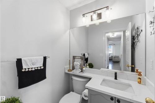 Vanity with a solid surface countertop, undermount sink, and a wall-mounted mirror - 522 Klarvatten Lake Wynd Nw, Edmonton, AB 
