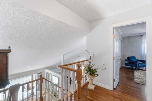 Hardwood flooring, white painted walls, white interior door, wood banister with white spindles, and an open stairwell - 522 Klarvatten Lake Wynd Nw, Edmonton, AB 