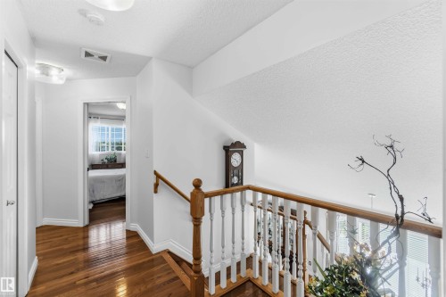 Hardwood flooring, painted trim, and a wood handrail with white balusters - 522 Klarvatten Lake Wynd Nw, Edmonton, AB 