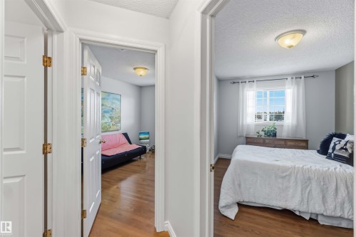 Interior hallway with wood-finish flooring, white paneled doors, and two rooms featuring ceiling-mounted light fixtures - 522 Klarvatten Lake Wynd Nw, Edmonton, AB 