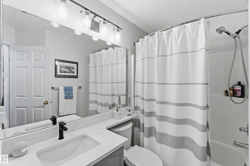 Bathroom featuring a single vanity with stone-finish countertop, undermount sink, and matte black faucet - 522 Klarvatten Lake Wynd Nw, Edmonton, AB 