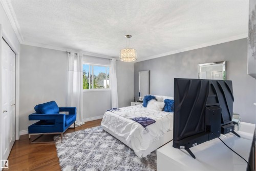 Generously sized window, wood-finish flooring, two-panel bifold closet doors, and crown molding - 522 Klarvatten Lake Wynd Nw, Edmonton, AB 