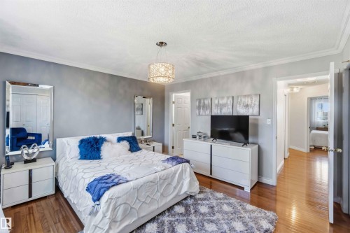 Wood-finish flooring, crown molding, a decorative ceiling light fixture, and a built-in closet with bi-fold doors - 522 Klarvatten Lake Wynd Nw, Edmonton, AB 
