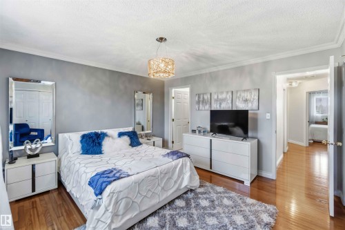 Hardwood-finish flooring, crown molding, a decorative pendant light fixture, built-in closet with mirrored doors, and a double-door entryway - 522 Klarvatten Lake Wynd Nw, Edmonton, AB 