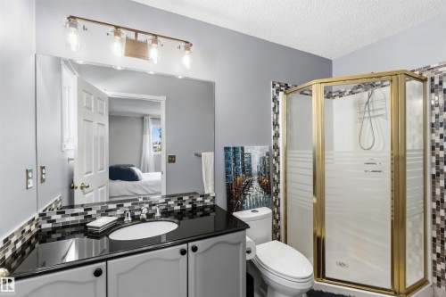 Vanity with an integrated sink, dark countertop, and mosaic tile backsplash - 522 Klarvatten Lake Wynd Nw, Edmonton, AB 