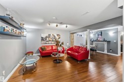 Spacious room featuring wood-finish flooring, track lighting, built-in shelving, decorative wall sconces, and a decorative fireplace - 