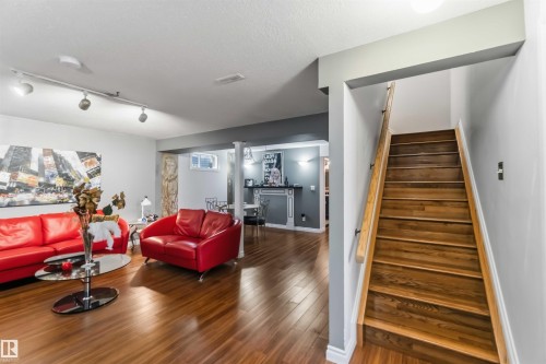 Wood-finish flooring throughout, track lighting, built-in wet bar, and wood staircase with handrail - 522 Klarvatten Lake Wynd Nw, Edmonton, AB 