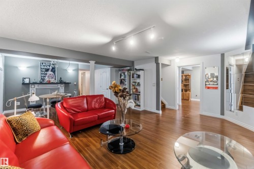 Spacious interior with wood-finish flooring, track lighting, built-in shelving, and a decorative mantelpiece - 522 Klarvatten Lake Wynd Nw, Edmonton, AB 