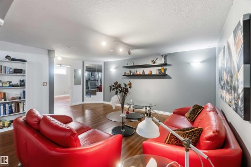 Wood-finish flooring, built-in shelving, wall-mounted display shelves, recessed lighting, and wall sconces - 522 Klarvatten Lake Wynd Nw, Edmonton, AB 