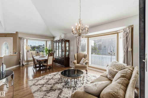 Expansive bay window, wood-finish flooring, vaulted ceiling, and an ornate crystal chandelier - 522 Klarvatten Lake Wynd Nw, Edmonton, AB 