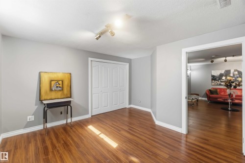 Wood-finish flooring throughout, light gray wall paint, white trim, and bi-fold closet doors - 522 Klarvatten Lake Wynd Nw, Edmonton, AB 