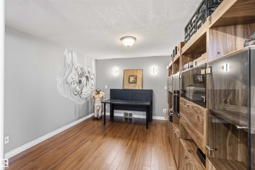 Wood-finish flooring, recessed ceiling lighting, wall-mounted sconces, and built-in cabinetry with glass-front uppers - 522 Klarvatten Lake Wynd Nw, Edmonton, AB 