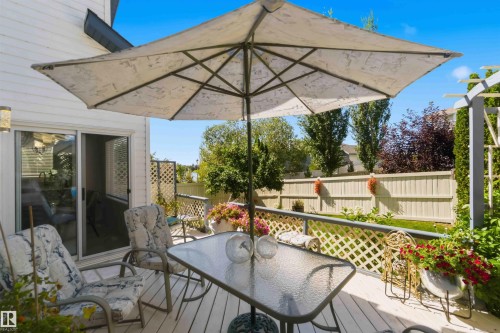 Expansive outdoor deck with white lattice railing and direct access to a manicured lawn - 522 Klarvatten Lake Wynd Nw, Edmonton, AB 