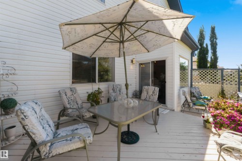 Rear deck with white wood-finish flooring, sliding glass door access, and lattice privacy screening - 522 Klarvatten Lake Wynd Nw, Edmonton, AB 