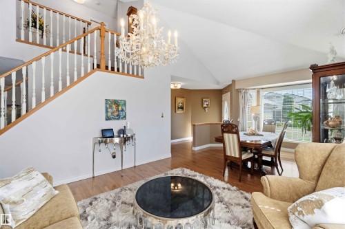 Vaulted ceiling with an elegant chandelier, wood-finish flooring, and a staircase with white spindles and wood handrails - 522 Klarvatten Lake Wynd Nw, Edmonton, AB 
