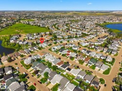 Residential street grid with numerous single-family homes, bordered by green spaces and a body of water - 