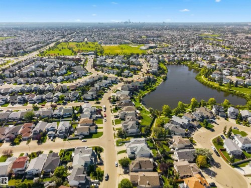 Residential neighborhood featuring a central lake, extensive green spaces, and a distant cityscape - 522 Klarvatten Lake Wynd Nw, Edmonton, AB 