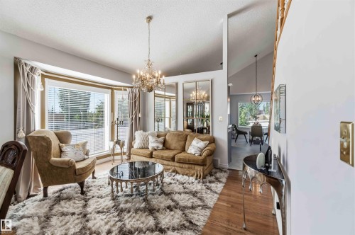 Expansive bay window, chandelier lighting, wood-finish flooring, and vaulted ceiling - 522 Klarvatten Lake Wynd Nw, Edmonton, AB 