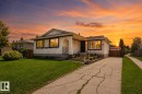 Stucco exterior with a peaked roofline, front garden bed, concrete driveway, and established front yard - 10439 36A Ave Nw, Edmonton, AB 