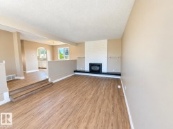 Wood-finish flooring throughout, a white brick fireplace with a dark hearth, and an arched entryway - 