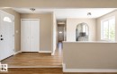 Wood-finish flooring throughout, entry door with decorative glass, bi-fold closet doors, arched doorway, and a double-pane window - 10439 36A Ave Nw, Edmonton, AB 