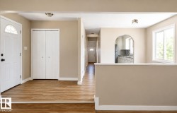 Wood-finish flooring throughout, entry door with decorative glass, bi-fold closet doors, arched doorway, and a double-pane window - 