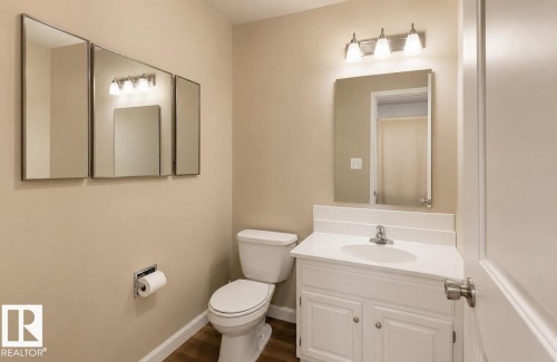White vanity with integrated sink, chrome faucet, and coordinating light fixture - 10439 36A Ave Nw, Edmonton, AB 