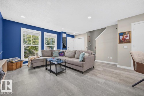 Bright living space featuring wood-finish flooring, recessed lighting, and dual pane windows - 1217 76 Street Sw, Edmonton, AB 