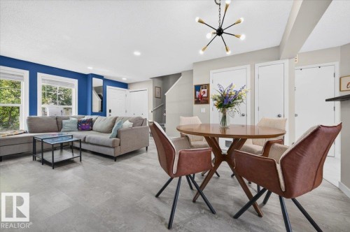 Recessed lighting, modern chandelier, multiple windows, wood-finish dining table, and gray tile flooring - 1217 76 Street Sw, Edmonton, AB 