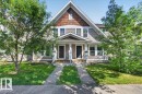 Two-story property featuring a gabled roofline with cedar shake accents, dual front entrances with covered porches, and mature trees framing the facade - 1217 76 Street Sw, Edmonton, AB 