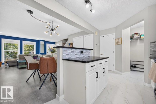 Kitchen island with dark countertop and mosaic tile backsplash - 1217 76 Street Sw, Edmonton, AB 
