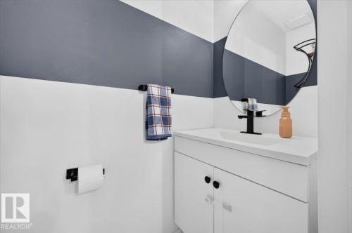 White vanity with an integrated sink, matte black faucet, and an oval mirror - 1217 76 Street Sw, Edmonton, AB 