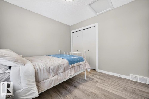 Neutral wall tones, wood-finish flooring, white trim, and a built-in closet with bi-fold doors - 1217 76 Street Sw, Edmonton, AB 