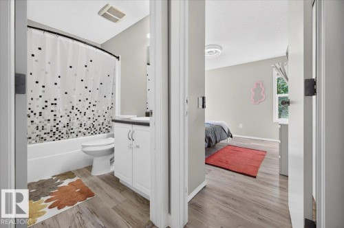Bathroom featuring a white vanity with a dark countertop and a full-size bathtub - 1217 76 Street Sw, Edmonton, AB 