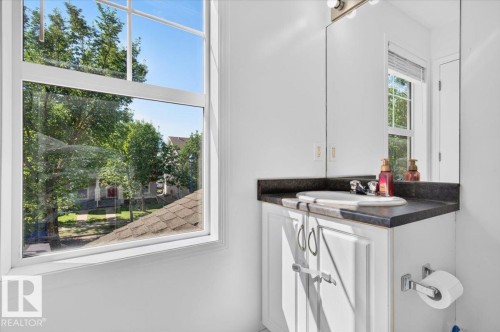 White vanity with cabinet storage, dark countertop, and integrated sink - 1217 76 Street Sw, Edmonton, AB 