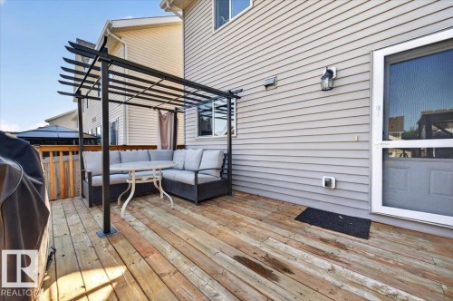 Expansive wood deck with a black metal pergola, privacy fencing, and exterior wall siding - 1217 76 Street Sw, Edmonton, AB 